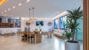 A spacious living area with a wooden dining table, sofas, and a large potted plant. - Ilios Suites (Hersonissos)