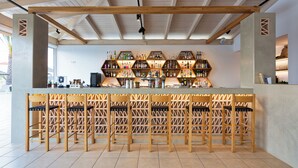 A bar area with wooden chairs and a bar counter displaying various bottles. - Ilios Suites (Hersonissos)