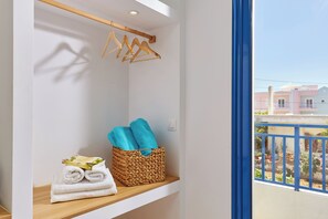 A bathroom with a wooden shelf holding towels and a woven basket with folded towels. - Ilios Suites (Hersonissos)