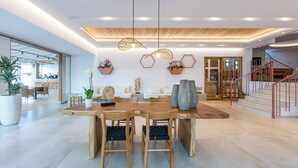 A spacious living area with a wooden dining table, two chairs, a sofa, and a staircase. - Ilios Suites (Hersonissos)
