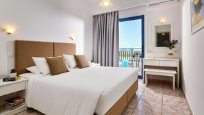A hotel room with a large bed, bedside tables, a small desk, a mirror, and a balcony view. - Ilios Suites (Hersonissos)