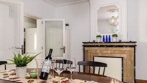 A dining area with a table set for two, a wine bottle, and glasses. There is a fireplace with decorative items on the mantel. - YourHouse Villa Magdalena (Cala Ratjada)