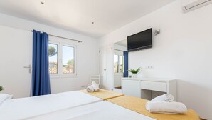 A hotel room with two beds, a TV, a desk, and a window with curtains. - YourHouse Villa Magdalena (Cala Ratjada)
