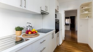 A modern kitchen with white cabinets, a built-in oven, and a countertop with a fruit bowl and kettle. - YourHouse Villa Magdalena (Cala Ratjada)
