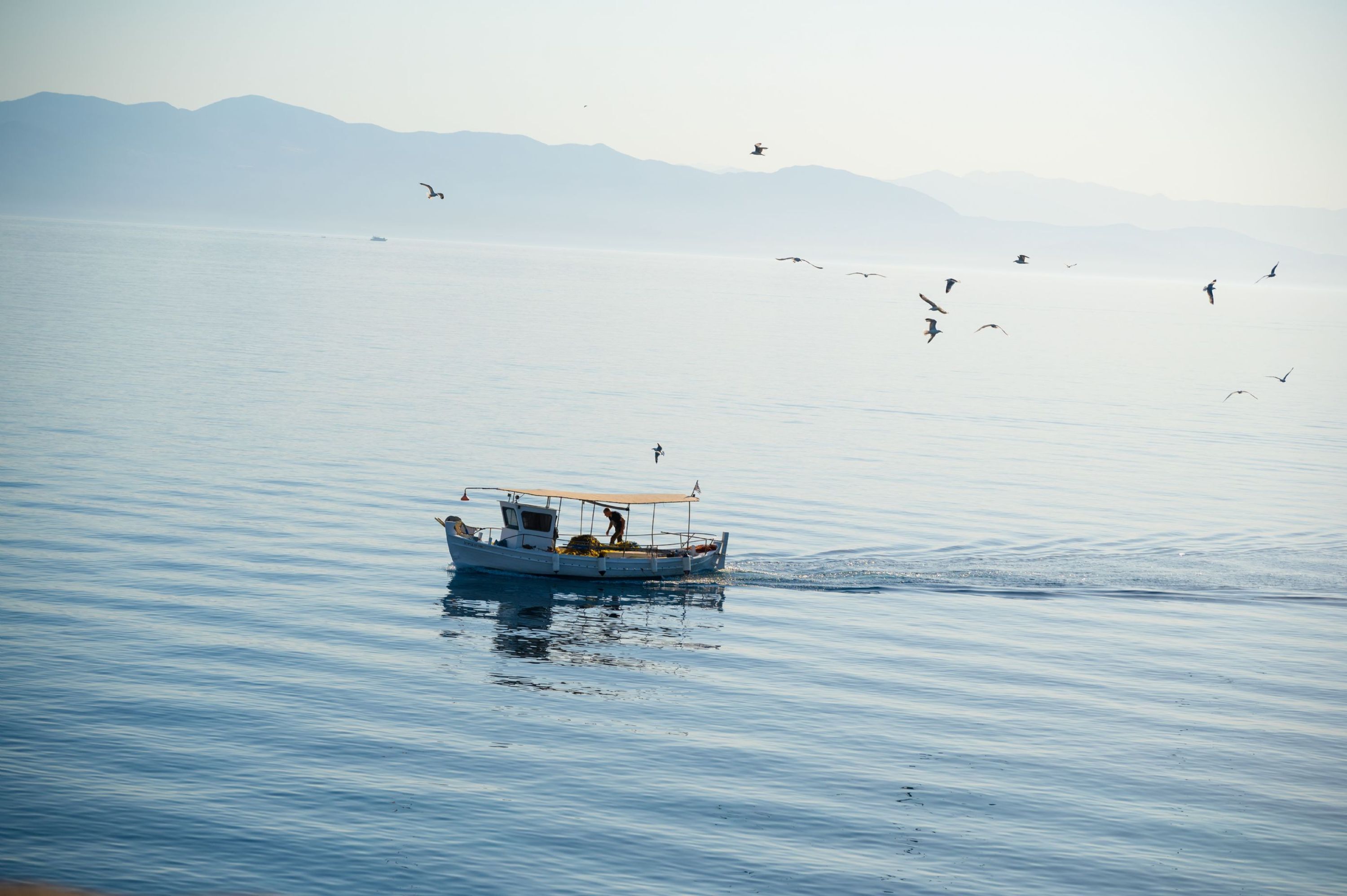 A boat on calm water with mountains in the background.