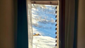 Ett fönster med utsikt över ett snötäckt landskap, en lampa och ett litet bord.