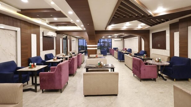 Un hall d’hôtel spacieux, doté de plusieurs espaces de détente, notamment des canapés et des tables, ainsi que d’une table basse centrale.