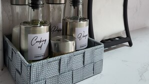 A set of cooking oil bottles in a woven basket, a metal container, and a black tray with a white cloth. - AMBIENCE STUDIO

 (Nairobi)