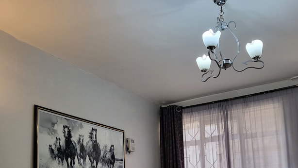 A bedroom with a bed, a nightstand, a heater, a chandelier, a window with curtains, and a painting on the wall. - AMBIENCE STUDIO

 (Nairobi)