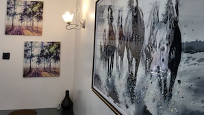 A room with a large framed painting of horses, a desk with drawers, and wall-mounted sconces. - AMBIENCE STUDIO

 (Nairobi)