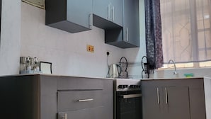 A kitchen with dark cabinets, a stove, and a window with curtains. - AMBIENCE STUDIO

 (Nairobi)