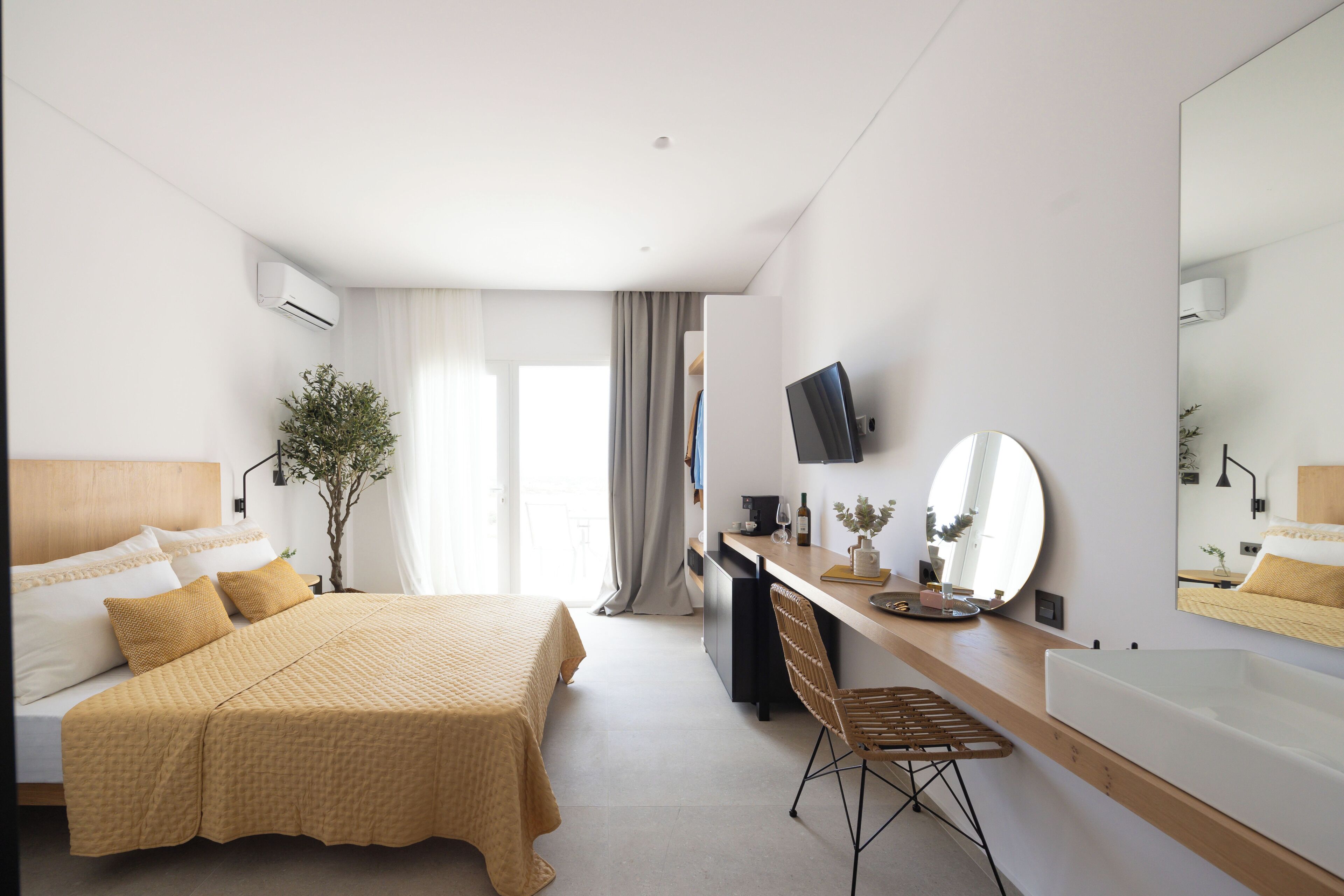 Een moderne hotelkamer met een bed, bureau, stoel en een grote spiegel.