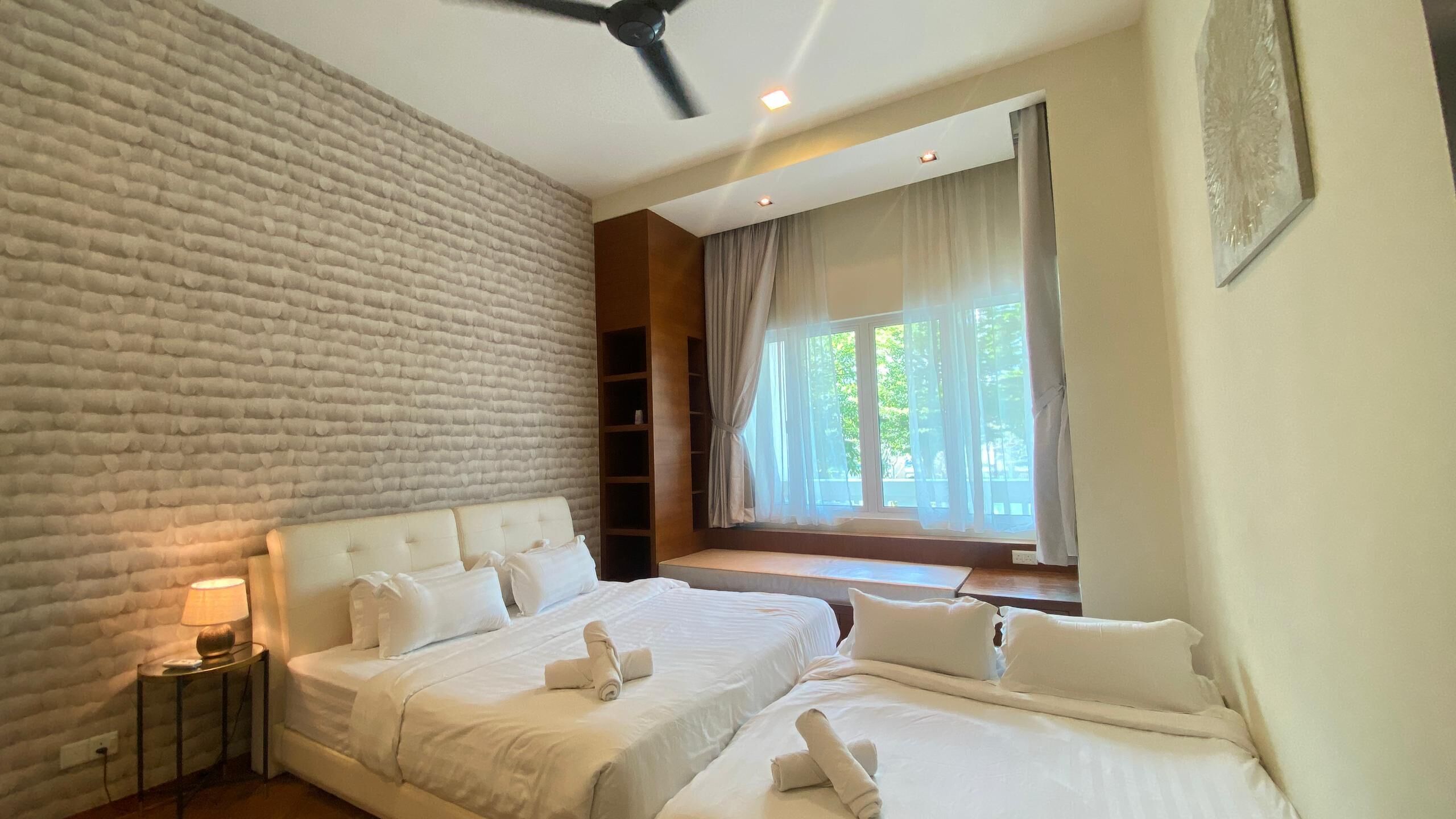 Habitación de hotel con dos camas, un ventilador de techo, una ventana con cortinas y una pared con textura.