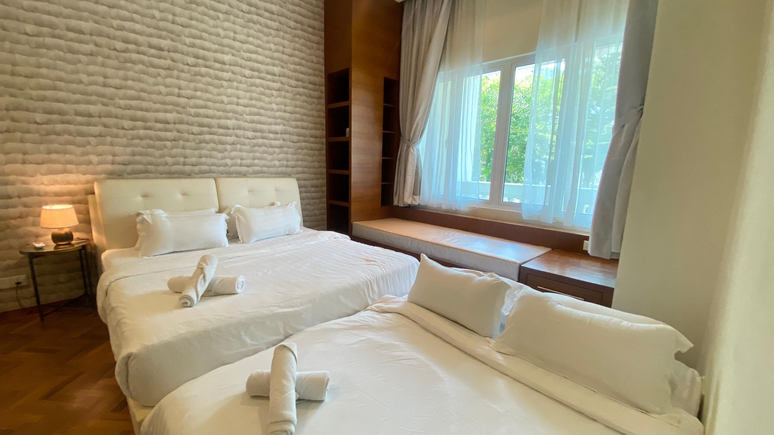 A hotel room with a large bed, a bedside table with a lamp, and a window with curtains.