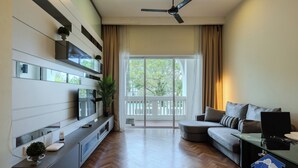 A modern living room with a sofa, a TV, a glass coffee table, and a ceiling fan. - The Suites Straits Quay (George Town)