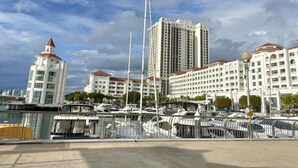 A marina with multiple boats docked, a tall building with a red roof, and several white buildings with red roofs in the background. - The Suites Straits Quay (George Town)
