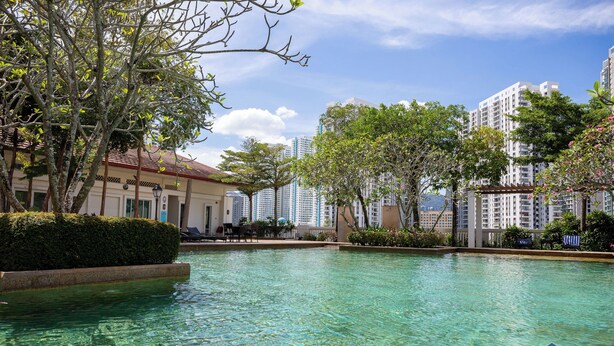 A swimming pool with clear water, surrounded by greenery and modern buildings in the background. - The Suites Straits Quay (George Town)
