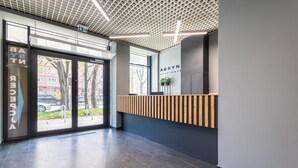 Un área de recepción moderna con un mostrador de madera, ventanas amplias y suelo de baldosas.