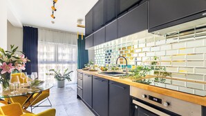 Una cocina moderna con armarios negros, encimera de madera y salpicadero de vidrio.