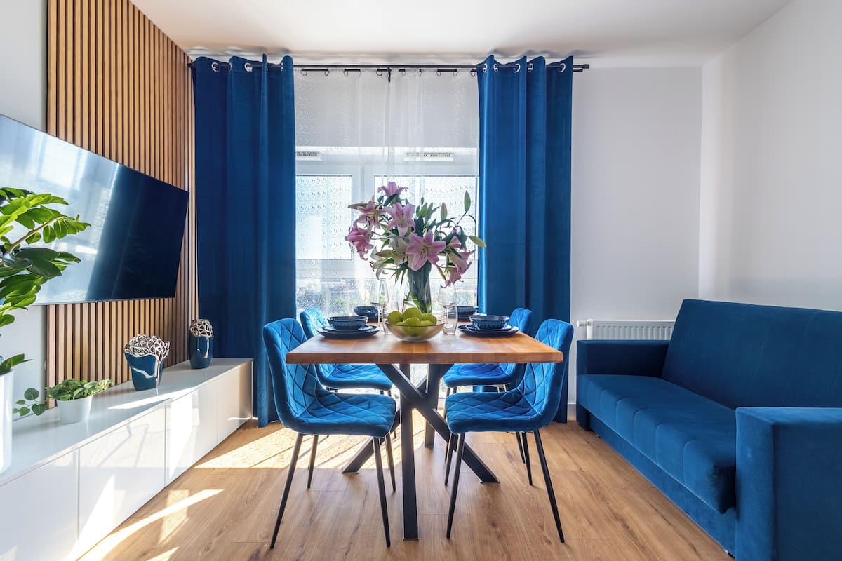 Una sala moderna con una mesa de comedor de madera, sillas azules y un sofá azul.