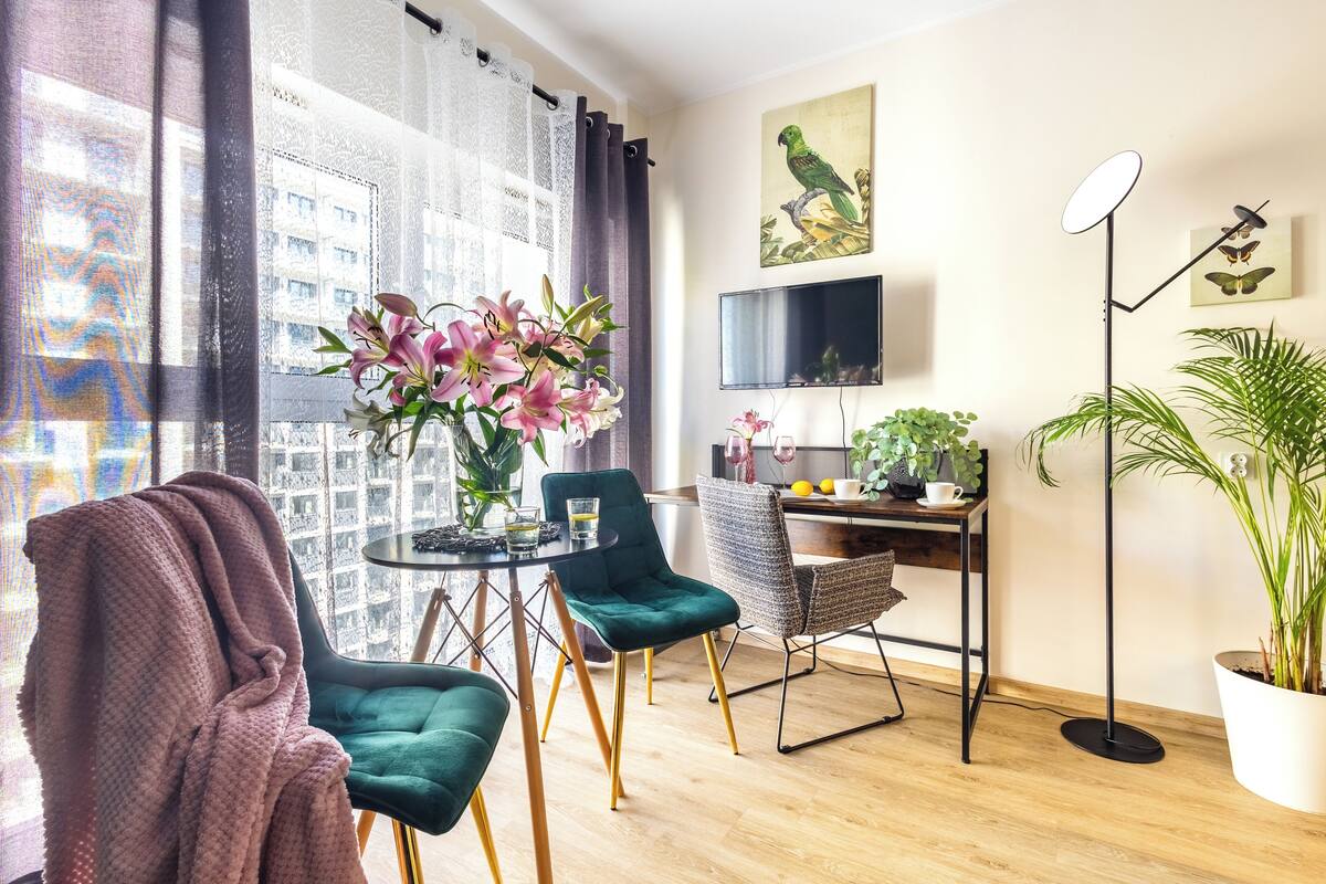 Una sala de estar moderna con un ventanal grande, un comedor, un televisor de pantalla plana y una planta en maceta.