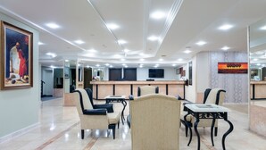 Un vestíbulo de hotel con mostrador de recepción, zona de estar y obras de arte en las paredes.