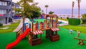 Un parque infantil con tobogán, estructuras para escalar y columpios.