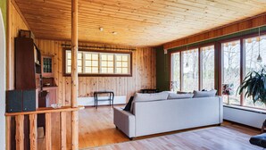 A wooden interior with a sofa, a table, and a window with a view of trees.