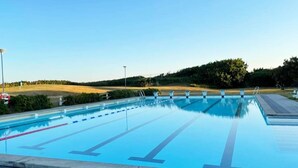 A swimming pool with lane dividers, a lifeguard stand, and a clear sky.