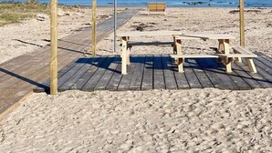A beach with a wheelchair-accessible sign, wooden benches, and a wooden walkway leading to the beach.