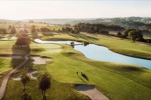 Un parcours de golf avec un étang, des arbres et un sentier.