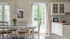 Eine helle Küche mit weißen Schränken, einem Esstisch mit Stühlen und einem großen Fenster.