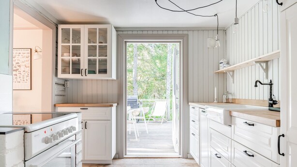 A kitchen with white cabinets, a stove, and a view of the outdoors.