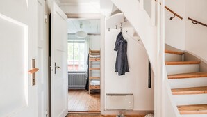 A hallway with a wooden floor, white walls, and a staircase with wooden steps and a white banister.