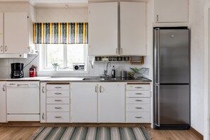 A kitchen with white cabinets, a stainless steel refrigerator, a coffee maker, and a radio.