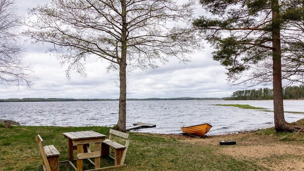 A lakeside setting with a wooden bench, a canoe, and a picnic table.