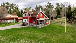 A red two-story house with a porch, a flagpole, and a grassy yard.