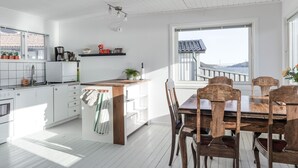 Een keuken met witte kasten, een houten eiland en een eethoek met houten stoelen en een tafel.