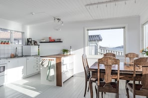 Une cuisine avec des meubles blancs, un îlot central en bois et un coin repas comprenant des chaises et une table en bois.