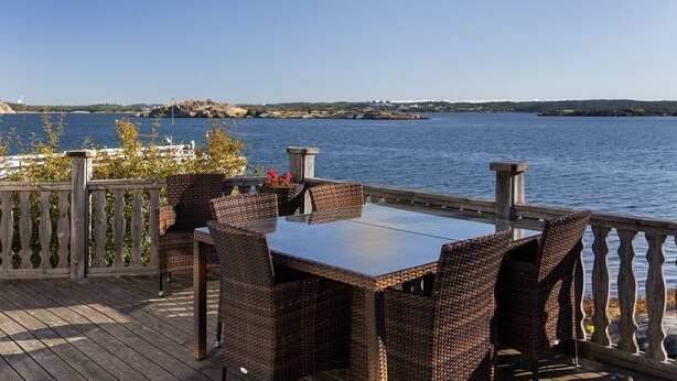 Een terras met rieten meubels en een tafel met uitzicht op een waterpartij.