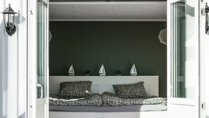 Een kamer met een ingebouwde bank, een klein raam en een deur.