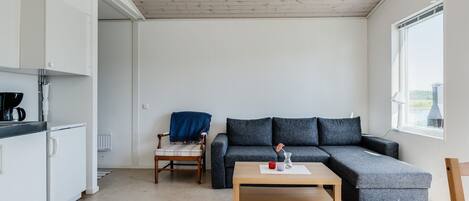 Una sala de estar moderna con un sofá seccional gris, una mesa de centro de madera y un tapete estampado.