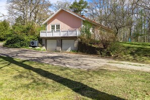Une maison de plain-pied à l’extérieur rose, dotée d’un porche et d’un garage.