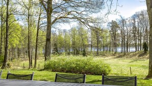Ein Essbereich im Freien mit Blick auf einen See und einen Wald.