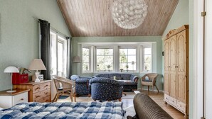 Ein Schlafzimmer mit einem Bett, zwei Sofas, einem Holzschrank und einem großen Fenster.