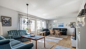 Ein modernes Wohnzimmer mit einer Couch, Sesseln, einem Couchtisch und einem Fernseher.