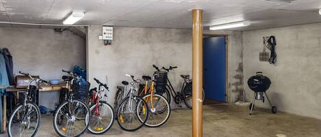A garage with bicycles, a barbecue grill, and a blue door.