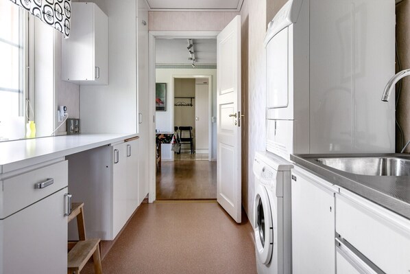 A compact kitchen with white cabinets, a washing machine, and a sink.