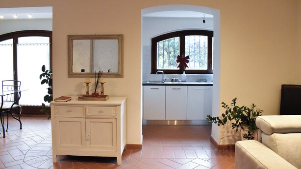 Une cuisine moderne avec des meubles blancs, un coin repas avec une table et des chaises, et un salon avec un canapé.