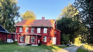 A red wooden house with a sloped roof, a front porch, and a gravel driveway. - StayNordic | Idyllic holiday house in Sundshult | SE09011 (Hedekas)